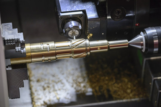 The CNC turning or lathe machine cutting groove slot at the brass shaft  by the milling spindle. Hi - technology manufacturing process.