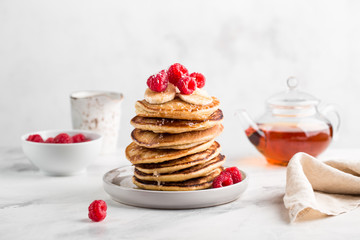 Stack of homemade pancakes with fresh raspberries on light concrete background
