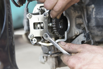 Hand holding the key, repairing the motorcycle engine in the garage, close-up