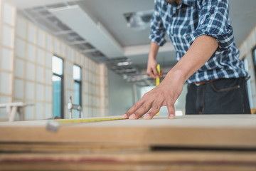decorator working on design and inspect of plywood at construction site; decorator checking material for interior