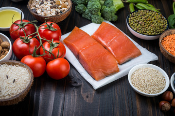 Fresh  fish, vegetables, fruits, nuts on wood  background.  Tomatoes, salmon,  spinach, sesame. Ingredients for healthy cooking. Healthy food concept.