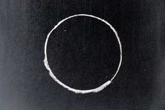 White chalk drawing in circle shape on black board background