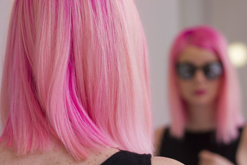 Pink hair girl with sunglasses looking in the mirror