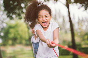 Happy children playing tug of war at the park