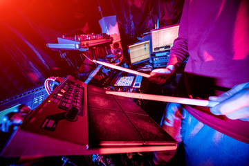 Young man playing on electric drum in sound recording studio.