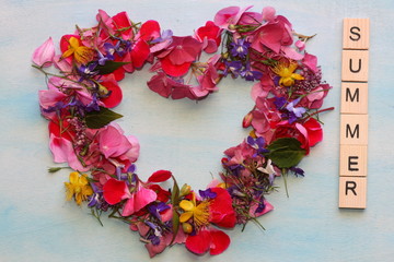 Heart of flowers with wooden letters. Summer frame.