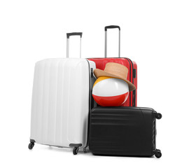 New suitcases with hat and inflatable ball packed for journey on white background