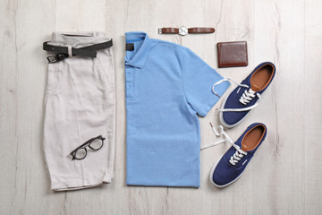 Set of stylish clothes and accessories on wooden floor, flat lay