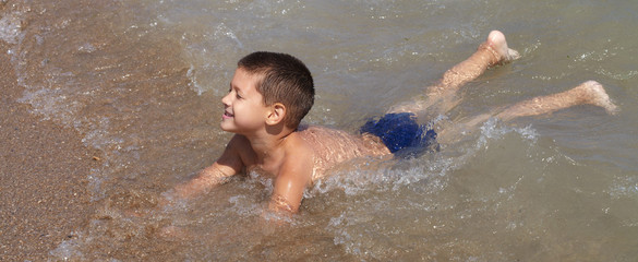 Little boy plays in the sea