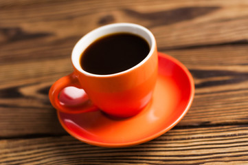 Full orange ceramic mug of black coffee on old wooden brown table
