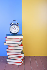 Science and education -  alarm clock high group of red books on the wooden table