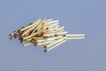 Wooden matches with a sulfur head in bulk and their reflection on the mirror surface