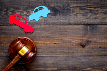 Car accident lawsuit concept. Two collided cars near judge gavel on dark wooden background top view...