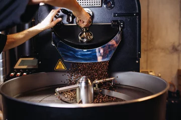 Foto op Aluminium Freshly roasted coffee beans pouring from a large coffee roaster into the cooling cylinder. © hedgehog94