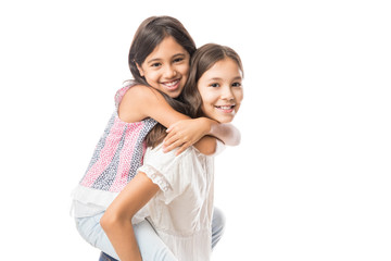 Cute young sister hugging older sister on white background