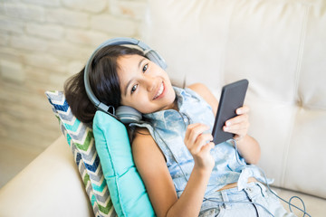 Relaxed girl listening to music sitting on a couch in the living room at home