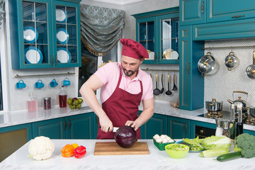 Man cut red cabbage with white knife. Handsome chef cut red cabbage. Red cabbage cut by knife. Man loves cooking fresh salad with cabbage for lunch. Red cabbage on cutting board. Healthy food concept