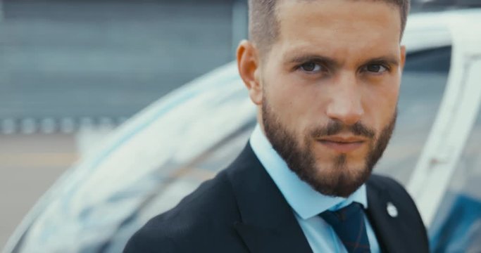 Portrait Of Young Adult Businessman Executive Standing Near A Private Charter Helicopter On A Helipad. 4K UHD