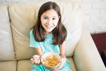 Closeup portrait of a young girl enjoying cereal cornflakes as snacks