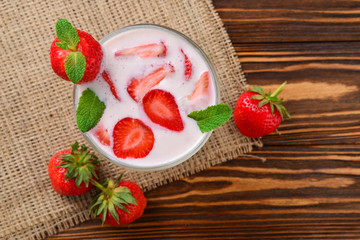 Homemade yogurt with fresh red strawberry on a wooden background. Top view.