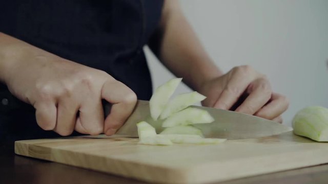 Close up of chief woman making salad healthy food and chopping cucumber on cutting board.