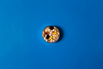 Assorted pharmaceutical medicine pills, tablets and capsules on blue background