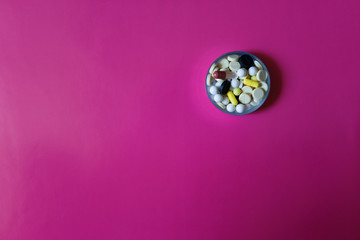 Assorted pharmaceutical medicine pills, tablets and capsules on pink background. Copy space for text
