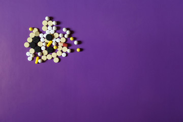 Assorted pharmaceutical medicine pills, tablets and capsules on purple background. Copy space for text