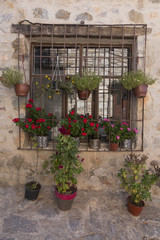 Fototapeta na wymiar A rustic wall and window with colorful flower pots in Datca, Turkey