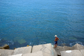 Fototapeta na wymiar Cádiz, Spain - June 21, 2018: A man trying to fish on the coast of Cádiz.