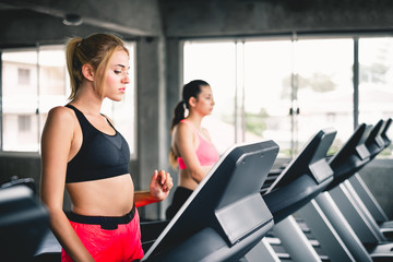Fototapeta na wymiar Woman walking and running on machine while cardio workout at sport gym