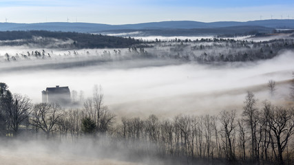 Fototapeta premium Wispy clouds and a dense fog blanket the early morning countryside in rural Garrett County, Maryland.