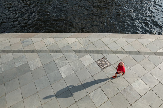 Male Jogger On Sidewalk With Long Shadow From Above -