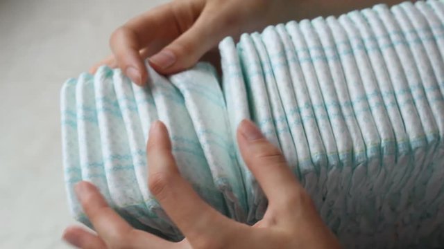 The girl counts an open pack with baby diapers, a close-up