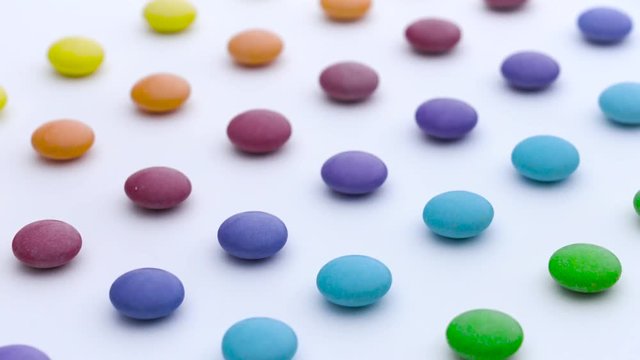 Colorful sweet round candies rows are moving diagonally on the white background.