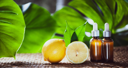 Bottles with lemon oil, fresh  fruit whole and half on a natural tropical background.