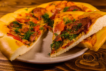 Ceramic plate with sliced homemade pizza on a wooden table