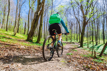 Fototapeta premium young woman ride bicycle in forest by trail