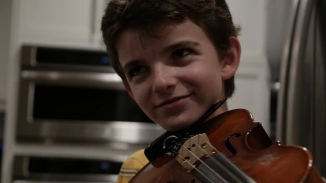 Proud young boy finishing a song on his violin and smiling
