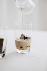 Frozen coffee ice cubes in a glass poured with milk to make a refreshing summer iced coffee drink. White background.