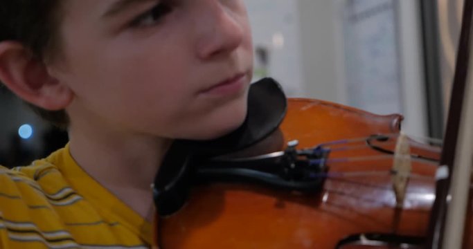 Cute young boy passionately playing the violin handheld