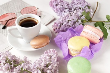 A cup of coffee on a saucer, macaroons, a bouquet of lilac. Breakfast. Close up