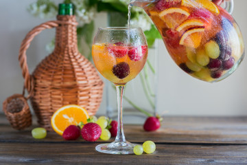 Homemade refreshing fruit sangria or punch with champagne, strawberries, oranges and grapes.