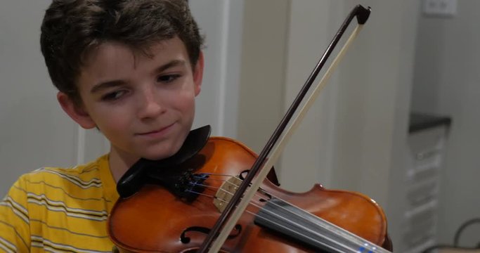 Pre teenage boy playing violin passionately