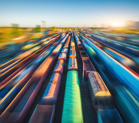 Aerial view of colorful freight trains at sunset. Cargo wagons with goods on railway station....