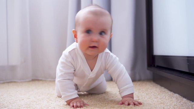 Funny baby girl crawling on carpet at home