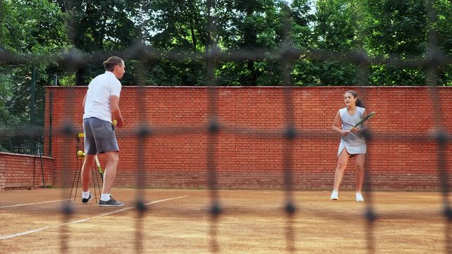Coacher teaching young girl to playing tennis.