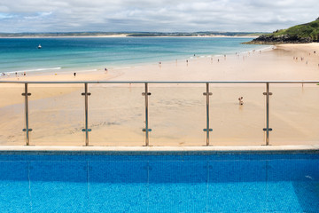 Vibrant blue hotel swimming pool at the edge of Porthminster Beach, St Ives, on a hot, Summer day.