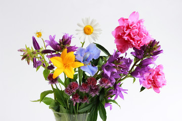 a bouquet of different wild field and garden flowers: chamomile, bell, lily, chives, iris, peony.