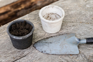 Black soil and flower pots intended for flower growing. Transplanting plants in a home garden.